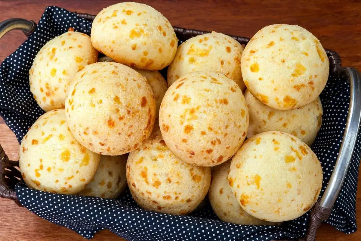 Cesta llena de pan de queso, bolitas doradas con trocitos de queso visibles, listas para disfrutar.
