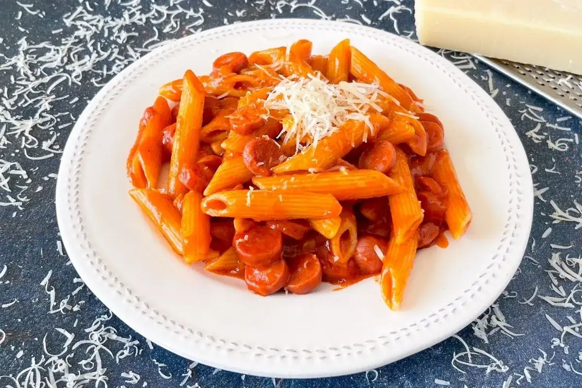 Macarrones con tomate y salchichas, cubiertos con queso rallado. Un plato sencillo y delicioso.