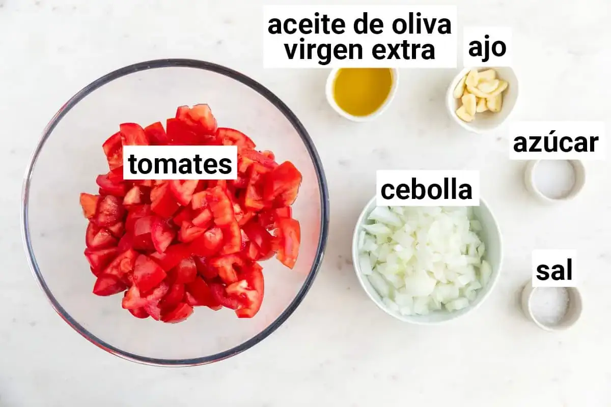 Ingredientes para una deliciosa salsa Emmy: tomates picados, cebolla, ajo, aceite de oliva virgen extra, azúcar y sal.
