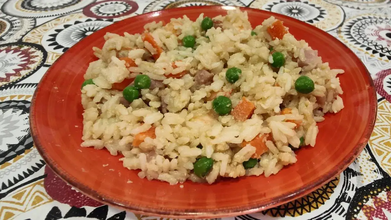 Un plato de arroz tres delicias con guisantes, zanahoria y trocitos de jamón.