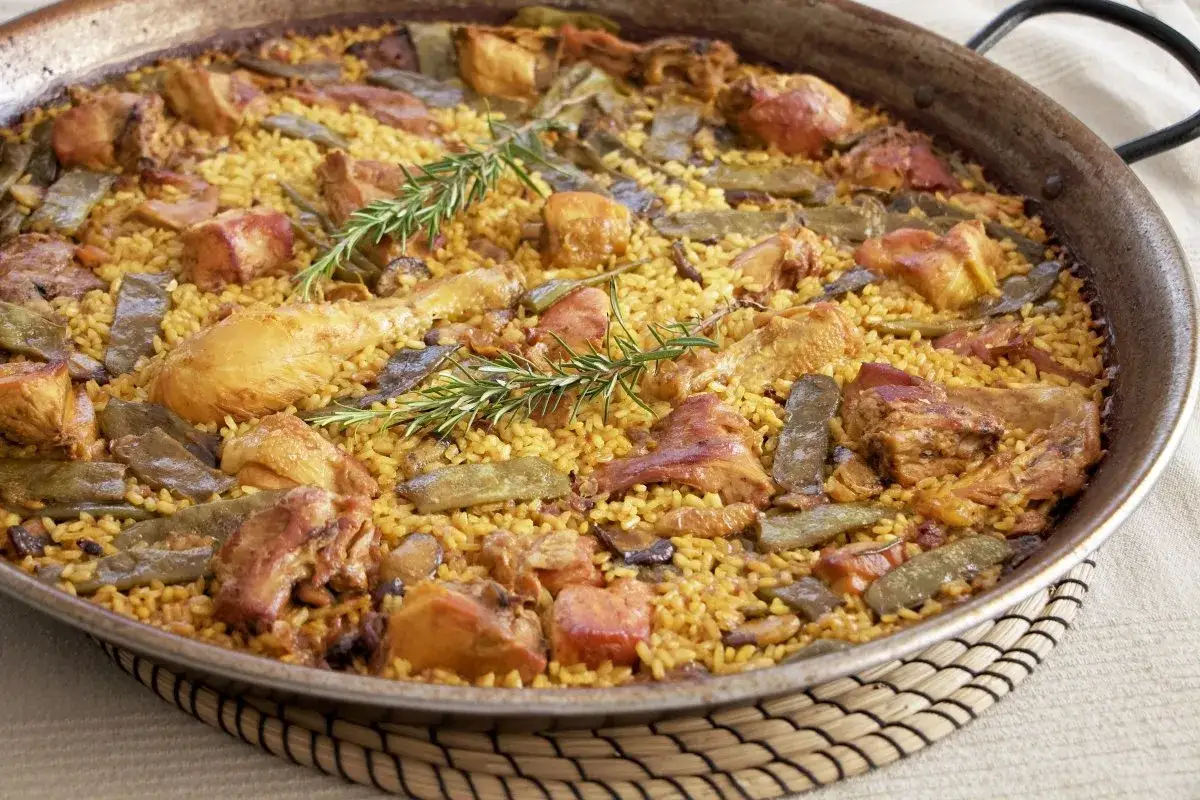 Paella de carne con pollo, jud&iacute;as verdes y romero, un plato tradicional espa&ntilde;ol lleno de sabor.