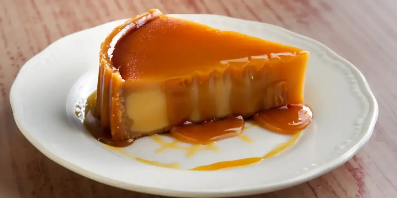 Rebanada de flan de leche condensada con caramelo líquido cayendo sobre un plato blanco.