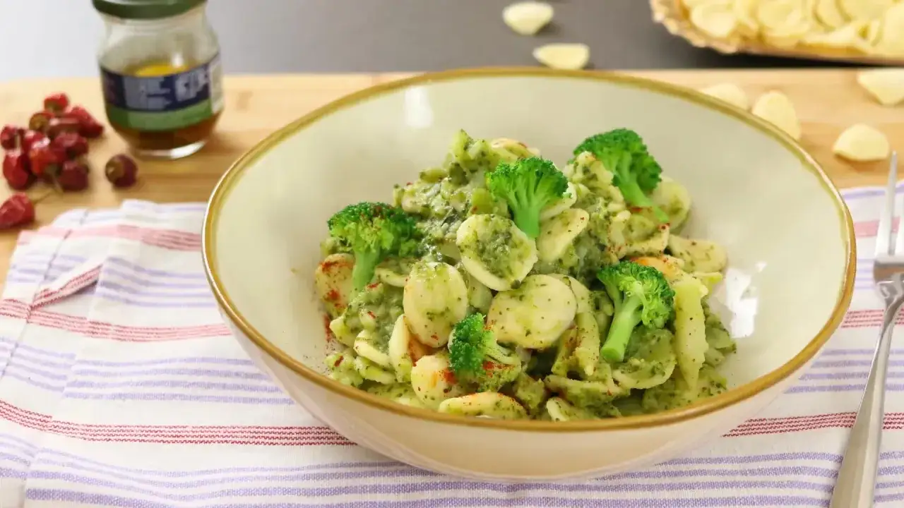 Un plato de pasta con brócoli, cubierto con una salsa verde cremosa y espolvoreado con pimentón.