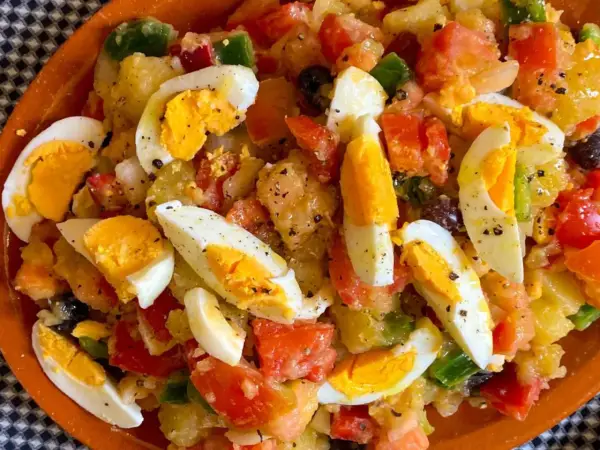Ensalada campera con patatas, huevos duros, tomate, pimiento y aceitunas. Ingredientes frescos y sabrosos.