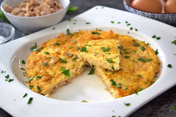 Tortilla de atún dorada y esponjosa, espolvoreada con perejil fresco. Un plato sencillo y delicioso.